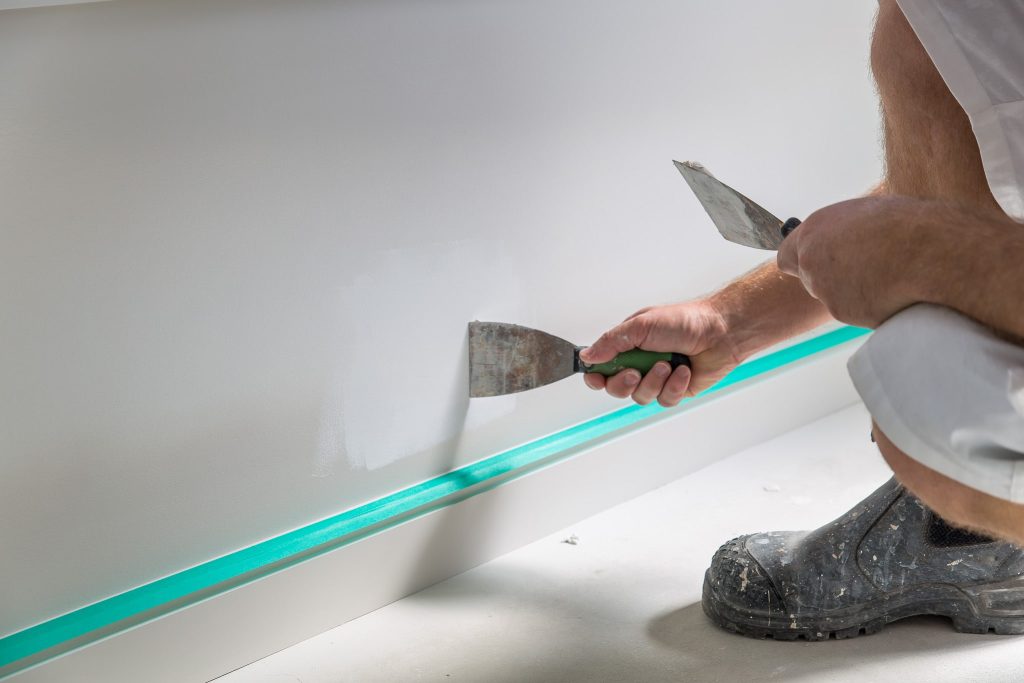 A plasterer from Auckland City Painters fills a defect in a plasterboard wall