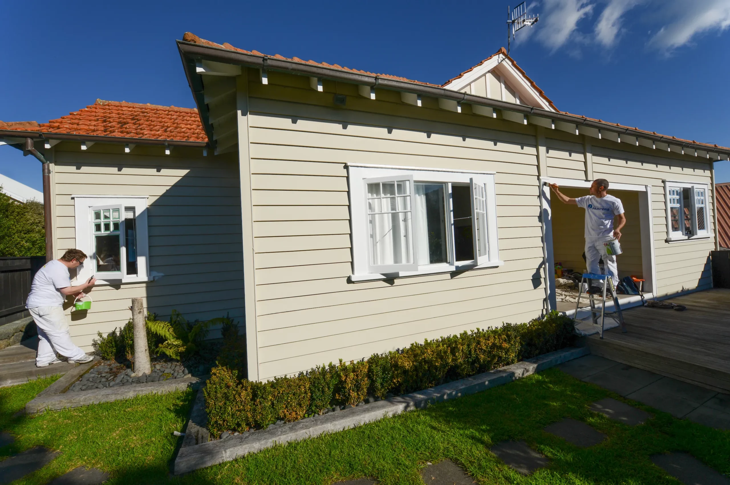 Two professional house painters painting a bungalow weatherboard home in Remuera