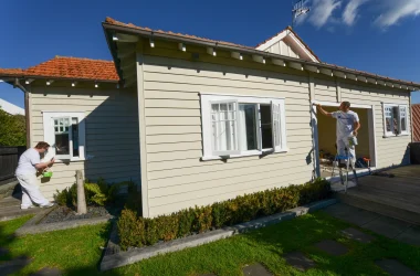 Two professional house painters painting a bungalow weatherboard home in Remuera
