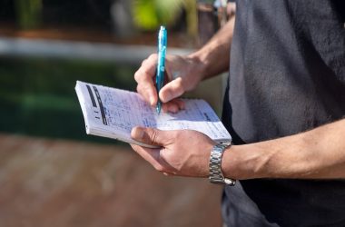 Close up of a house painters hands writing measurements on a notebook.